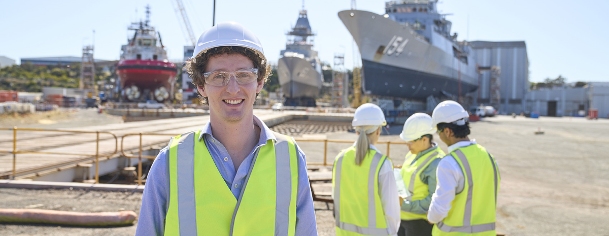 drafter trainee standing in front of ship yard